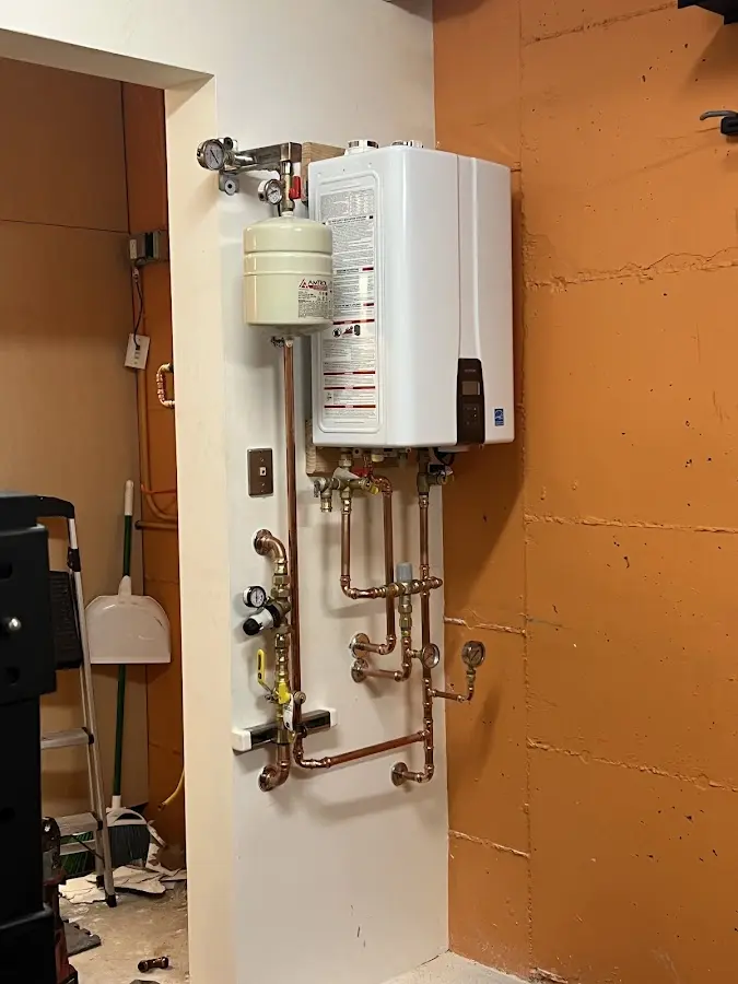 Plumbing technician inspecting water heater connections in Mahoning